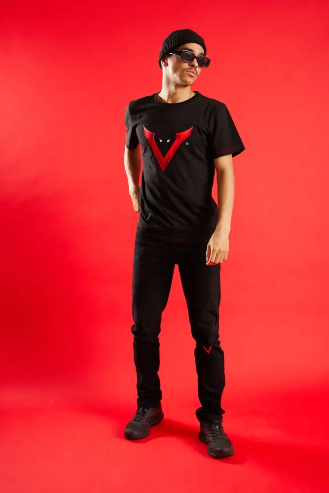 Model wearing the Verrati signature tee, full length on a red backdrop