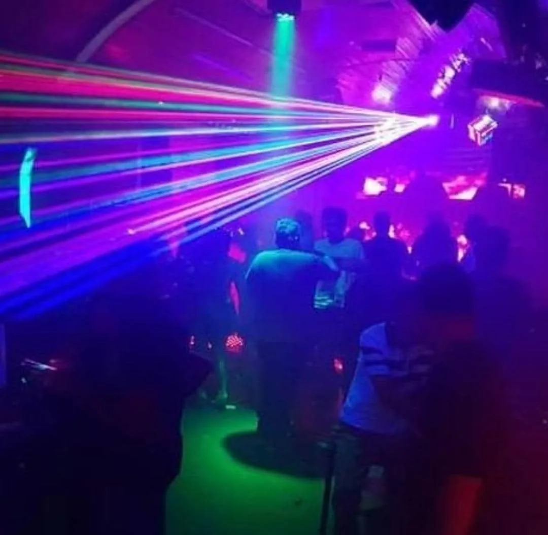 Crowd on the floor under a fan of coloured lasers